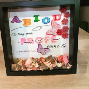 Cuadro artesanal con dedicatoria para profesora, letras coloridas, flores de papel, mariposas y mensaje personalizado de agradecimiento